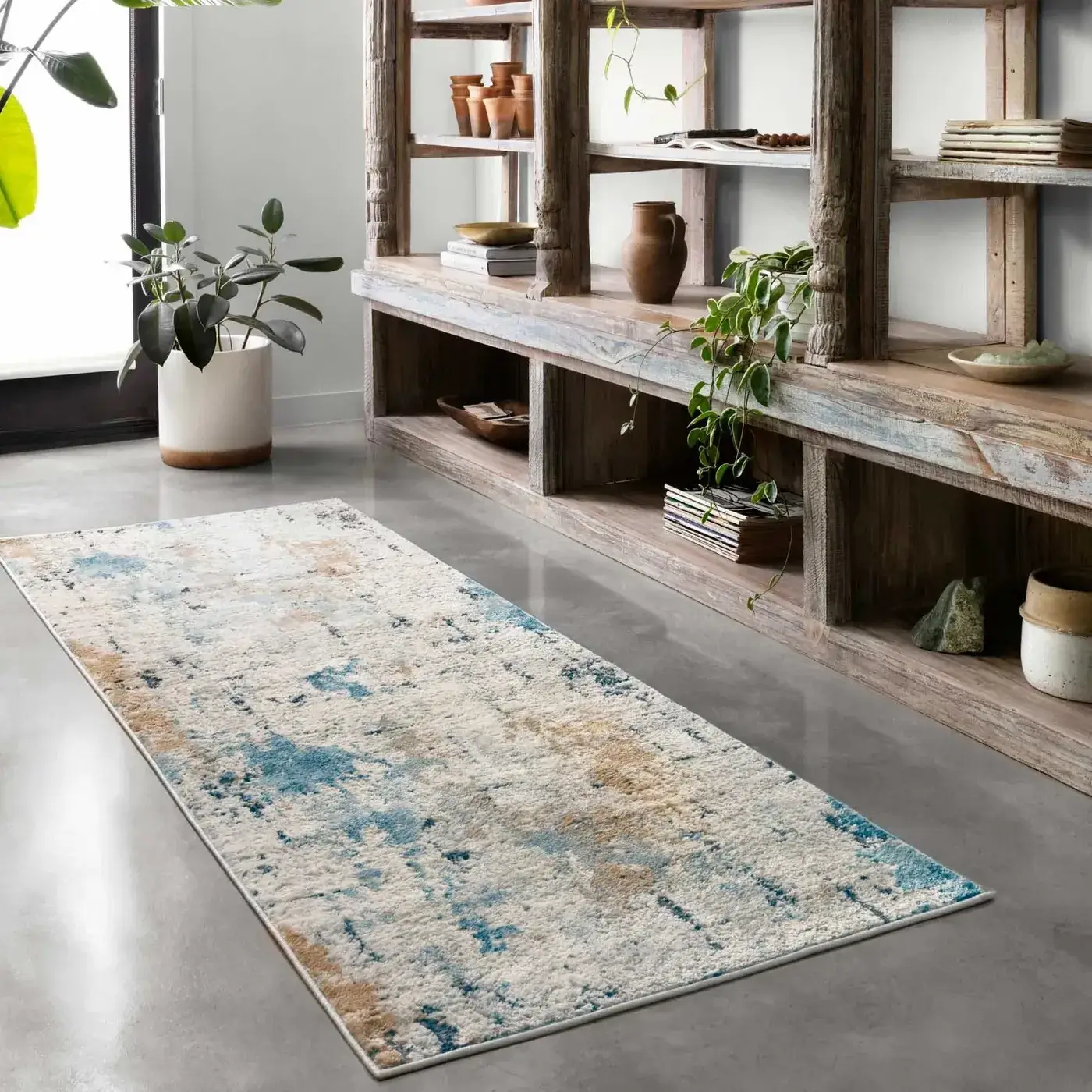 ALCHALC-01SNSL__5Broomscene_5D_3_1400x Loloi area rug in a distressed white, blue, and brown abstract pattern, placed as a runner in a room with a large wooden shelving unit.