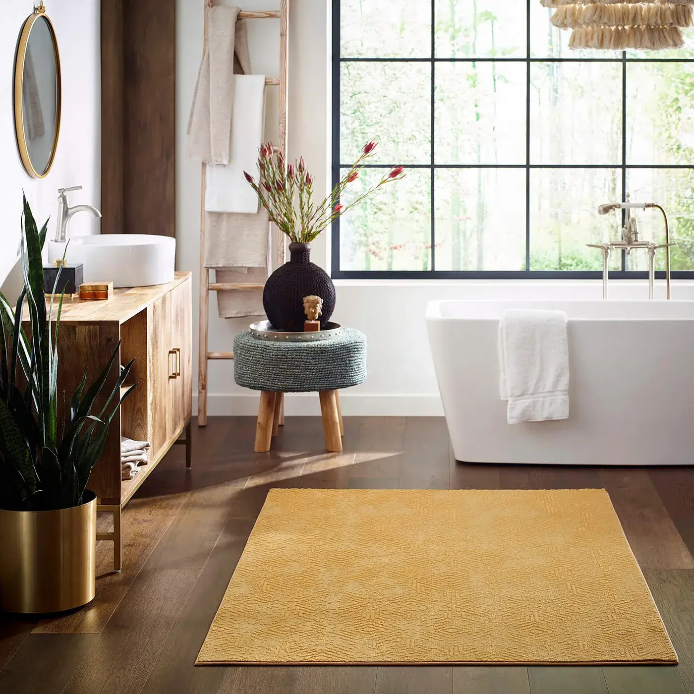 Boho Chic Bathroom-Vintage Revival-CC77B-00250-Exquisite-FH820-7054-Cascade-BATHROOM-H copy A vibrant yellow Shaw Floors area rug with a subtle geometric pattern lies on a dark wood floor in a bohemian-style bathroom with a white freestanding tub, wooden vanity, and large window.