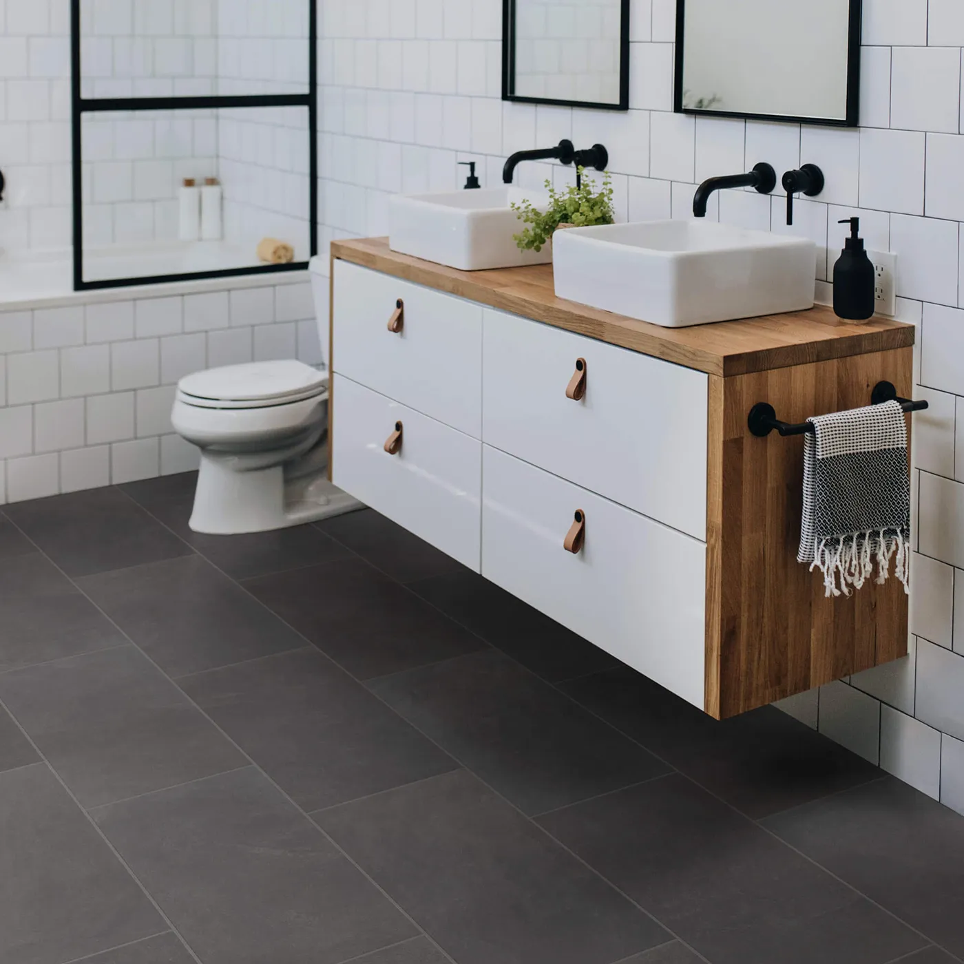 Callisto-12x24-430TS-Ember-00900-RM-V Shaw Floors Ember dark gray rectangular tile in a modern bathroom with white subway tile walls and a floating wood vanity.