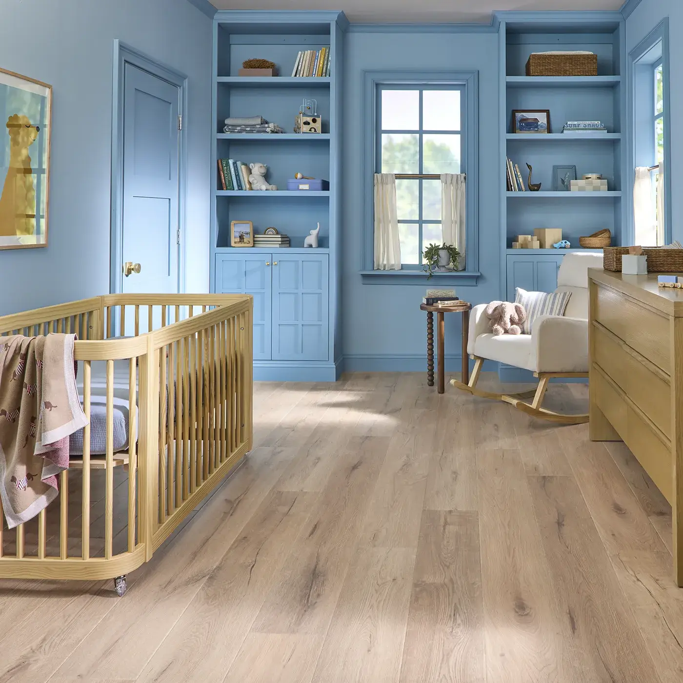 UV810_05024_Room COREtec Luxury Vinyl in a light natural wood color in a child's bedroom or nursery with blue walls and a light wood crib.