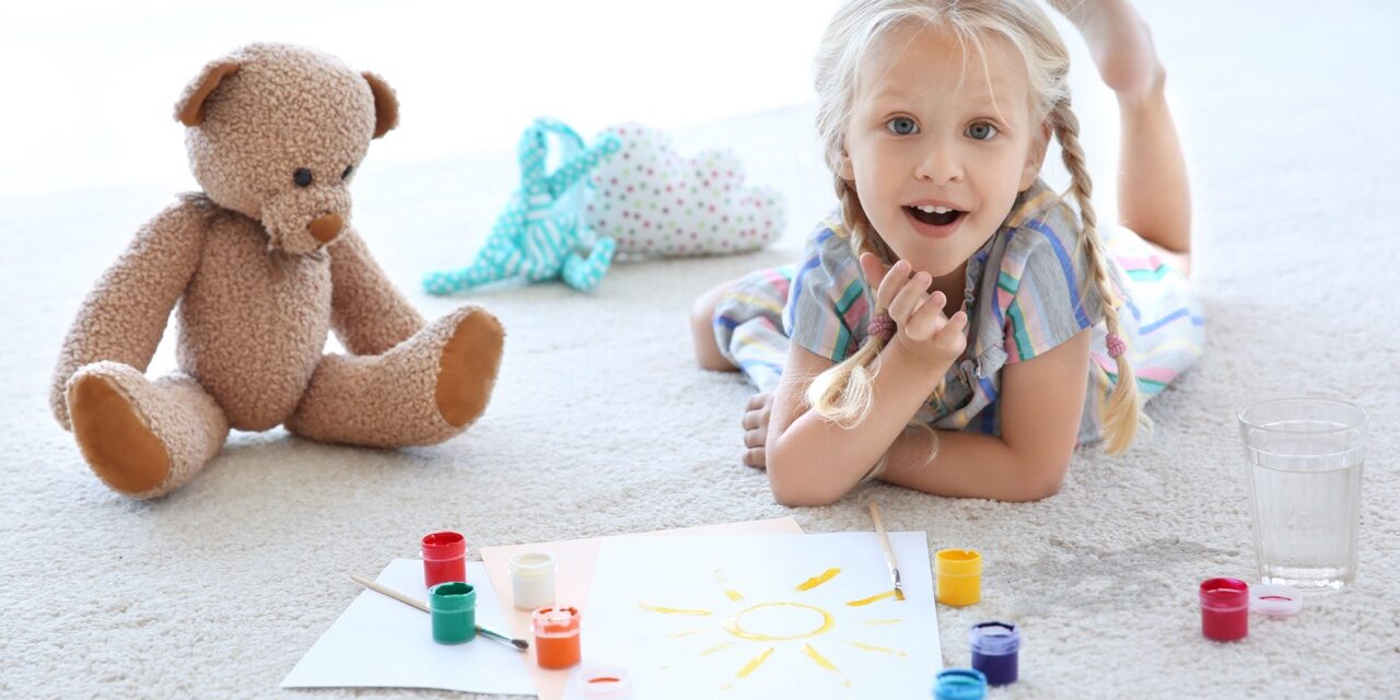 Cute little girl painting picture and spilled water on carpet