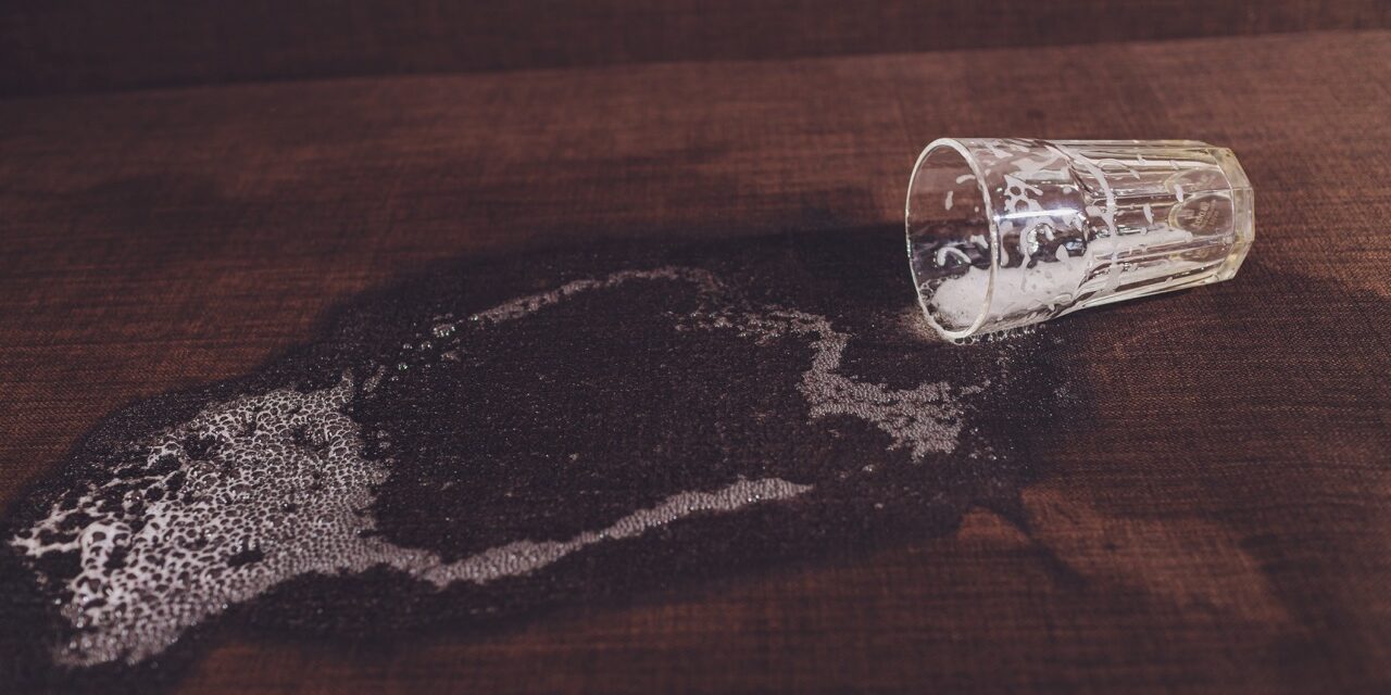 Alcoholism in the family. Beer bottle and spilled beer in the sofa